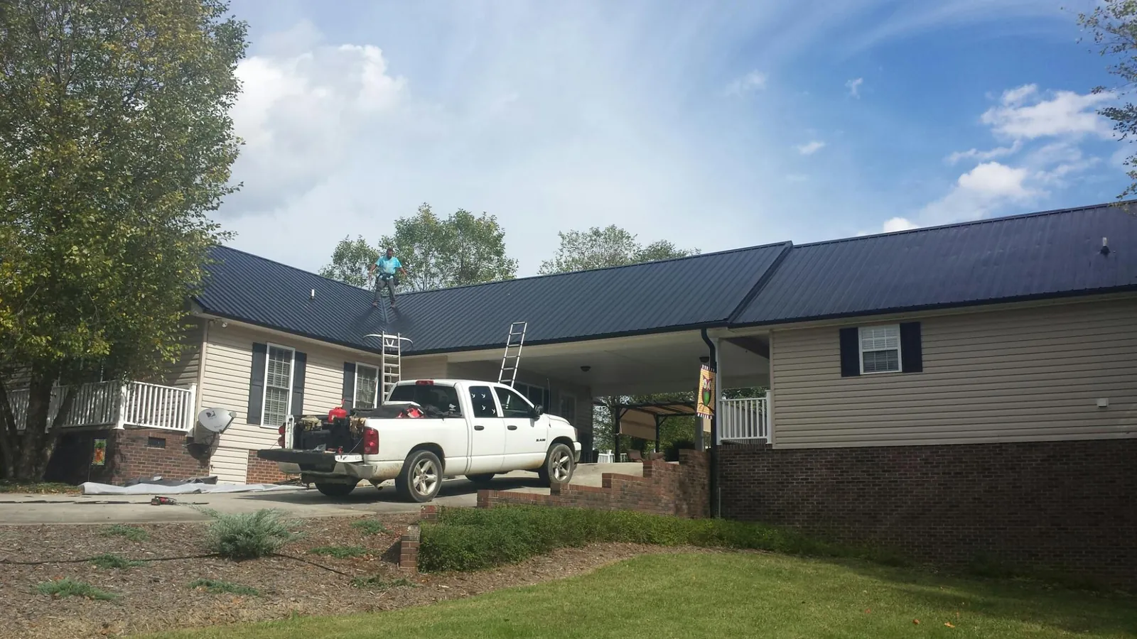 Black metal roof over a home and attached breezeway with ladders set in Richmond
